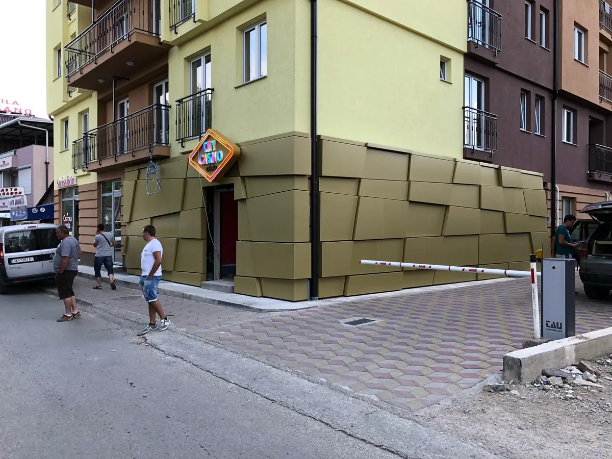 Colț de clădire placat integral cu casete luminoase aurii, la nivelul străzii — Lartek Grup